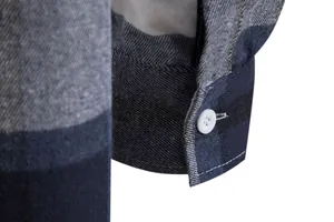 Primo piano del polsino di una camicia a quadri con cuciture e bottone bianco.