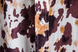 Detail macro shot of a men's shirt showing brown cow print and white button stitching