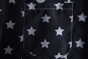 Detail of black short sleeve shirt featuring white star print and pocket stitching.