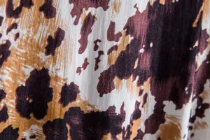 Macro view of abstract brown and tan floral print on breathable men's shirt fabric
