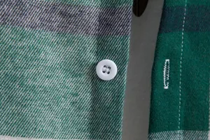 Primo piano macro di un bottone bianco e trama del tessuto su una camicia a quadri