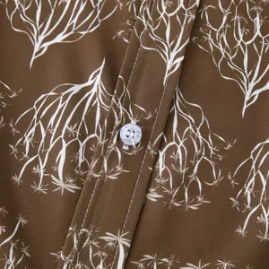 Détail d'une chemise hawaïenne marron avec motif de branches blanches.