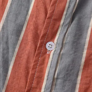 Close-up of vertical striped fabric and button on Hawaiian style men's beach shirt.