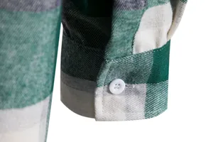 Primo piano del polsino di una camicia di flanella a quadri verdi con bottone bianco e tessuto