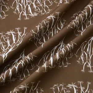 Gros plan du tissu de chemise hawaïenne marron avec détails de motifs d'arbres blancs.