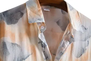 Close-up of men's summer casual shirt featuring artistic orange and grey abstract floral print