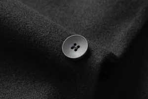Close-up of high-quality button and wool fabric texture on a men's winter overcoat