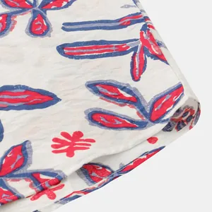Dettaglio ravvicinato del tessuto della camicia in cotone bianco con fiori rossi e blu