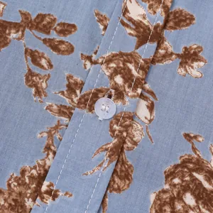 Detailaufnahme von Knöpfen und braunem Blumendruck auf blauem Hawaiihemd-Stoff für Herren