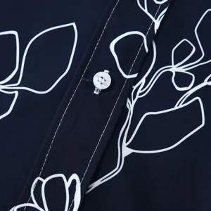 Gros plan détaillé montrant le bouton blanc et l'imprimé floral d'une chemise hawaïenne bleue