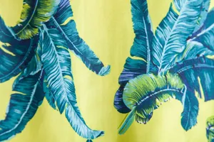Detailed view of tropical banana leaf print on a vibrant yellow Hawaiian shirt fabric