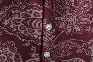 Close-up macro shot of burgundy paisley print fabric and buttons on a men's casual shirt