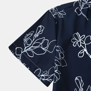 Gros plan sur l'imprimé floral blanc d'une manche de chemise hawaïenne bleu marine pour homme.