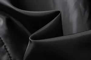 Close-up of high-quality black fabric texture for men's winter trench coat detail view.