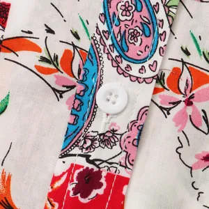 Close-up detail of colorful paisley floral print and white button on men's summer shirt.