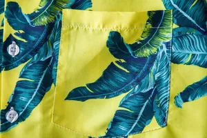 Macro detail of a vibrant Hawaiian shirt featuring tropical leaf prints and pocket stitching.
