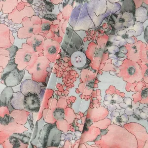Primo piano del motivo floreale colorato e del bottone bianco sul dettaglio della camicia da uomo