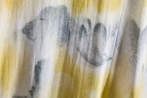 Macro view of artistic yellow and grey tie-dye pattern on breathable summer shirt fabric