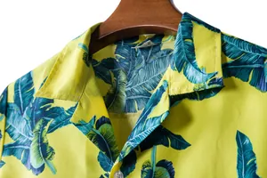Close-up of yellow Hawaiian shirt collar with tropical teal leaf pattern.