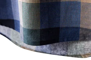 Macro view of the finely stitched curved hem on a plaid cotton linen casual shirt.