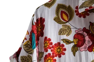 Close-up macro view of vibrant red floral pattern and fabric texture on a white summer shirt.