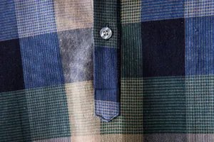 Close-up detail of plaid cotton-linen shirt showing fine fabric texture and button placket