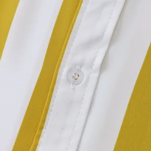 Primo piano di un bottone bianco sul tessuto a righe gialle e bianche di una camicia