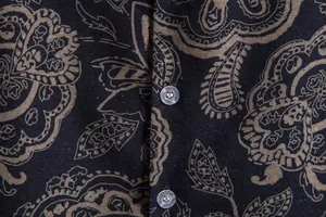 Close-up of men's vintage paisley print shirt fabric with clear buttons and texture.