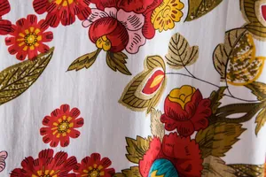 Close-up of vibrant floral pattern on white cotton blend men's casual shirt fabric texture.