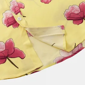 Close-up detail of the hem and pink floral print on a yellow short-sleeved shirt