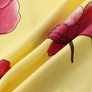 Macro detail view of red floral patterns and fabric texture on a yellow men's shirt