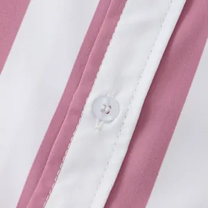 Dettaglio macro dell'abbottonatura di una camicia a righe bianche e rosa con bottone