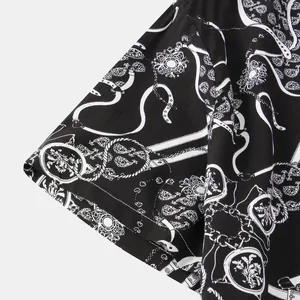 Dettaglio di camicia da uomo a maniche corte con stampa barocca e catene bianche su nero.