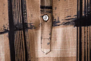 Macro detail of men's casual brown linen-blend shirt showing fabric texture and button