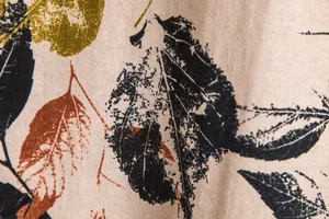 Close-up of vintage leaf print on breathable linen-textured fabric for men's shirt.