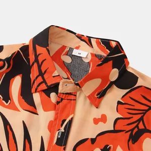 Close-up view of a vibrant tropical leaf print men's shirt collar showing the size M label