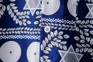 Macro detail of blue ethnic print Hawaiian shirt fabric with white button accent
