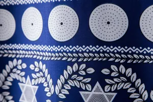 Macro detail showing the intricate blue and white ethnic print pattern of a men's Hawaiian shirt