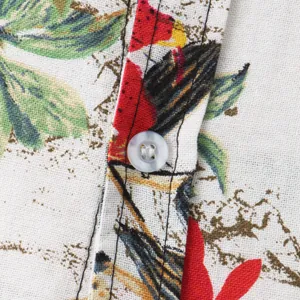 Detalle macro de una camisa de playa para hombre con estampado floral tropical y botón blanco