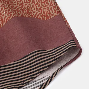 Detailed view of ethnic patterned shirt fabric with striped hem and rich texture.