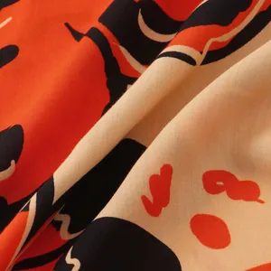 Macro view of men's summer floral shirt fabric showing vibrant orange and black print
