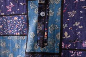 Macro detail of blue floral patchwork linen fabric showing texture and button on men's shirt