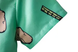 Close-up detail of green Hawaiian short sleeve shirt showing cuff stitching and print.