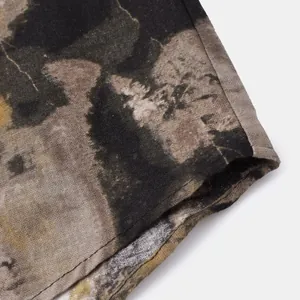 Macro detail of men's linen floral shirt cuff showing earthy tie-dye print and texture