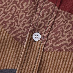 Macro view of the ethnic floral pattern fabric and white button on this men's casual shirt
