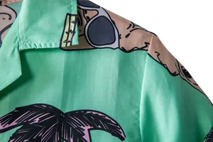 Close-up of mint green Hawaiian shirt fabric with palm tree and sunglasses prints