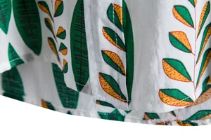 Close-up macro view of green and yellow tropical leaf print on white casual shirt