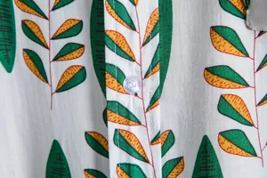 High-quality close-up detail of leaf print fabric and button on men's casual shirt