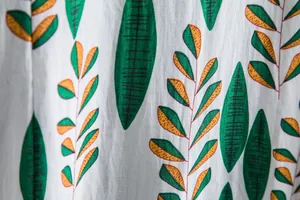 Macro detail of breathable cotton fabric with green and orange leaf pattern print