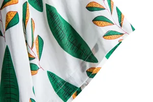 Close-up view of vibrant tropical leaf print and fine stitching on white casual shirt
